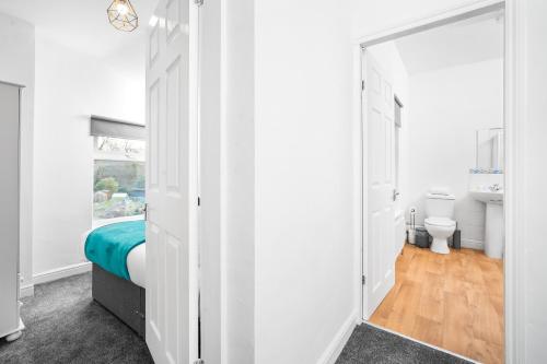 a white room with a bed and a bathroom at Harborne 2 Bedroom House - Parking - Smart TV - Wifi - 62W in Birmingham