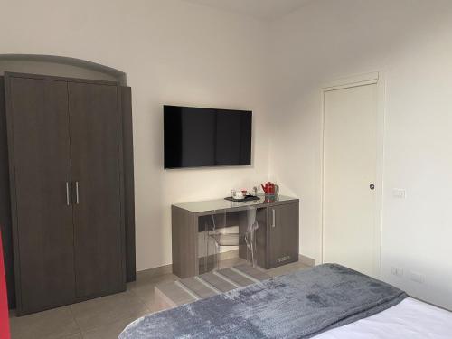 a bedroom with a desk and a tv on the wall at 54 ROSSELLI ROOMS in La Spezia