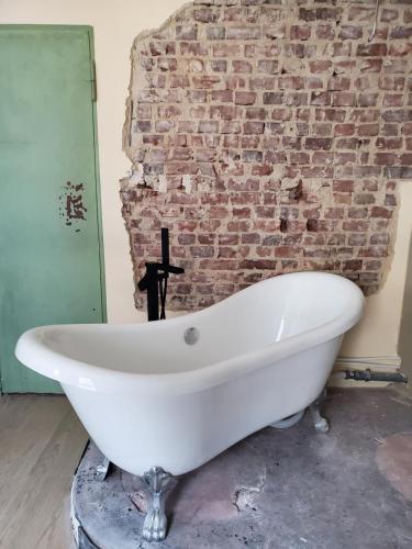 a white bath tub sitting in front of a brick wall at Stunning Industrial Loft in a former Power Plant in Essen