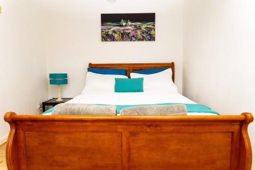 a bedroom with a wooden bed with blue pillows at Spacious 4 Bed Home in Milton Keynes -free parking in Milton Keynes