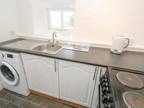 a kitchen with a sink and a washing machine at Toadstools in Penryn