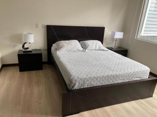 a bedroom with a large bed with two night stands at Suite La Carolina QUITO in Quito