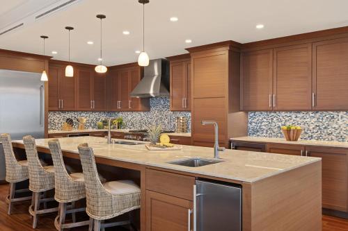 a kitchen with wooden cabinets and a large island with a sink at Timbers Kauai Ocean Club & Residences in Lihue