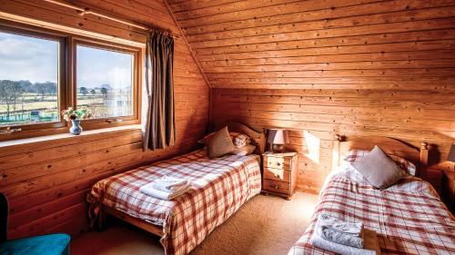 a bedroom with two beds in a wooden cabin at The New Farmhouse in Biggar