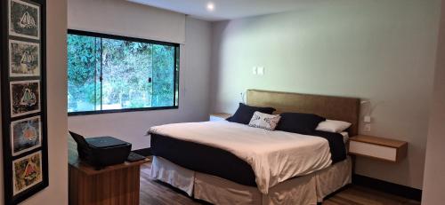 um quarto com uma cama e uma grande janela em Paraíso no Rocio na Reserva Florestal de Araras em Petrópolis