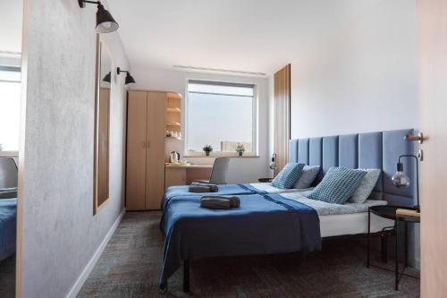 sypialnia z łóżkiem z niebieską pościelą i oknem w obiekcie Sapphire Room Hotel Lechicka w Poznaniu