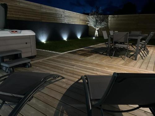 a deck with chairs and a table and a tree at Villa Bréhat vue mer et jacuzzi in Tréveneuc