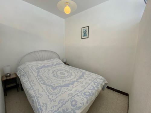 une chambre avec un lit avec une couverture bleue et blanche dans l'établissement Appartement Climatisé avec Balcon, Parking Privé, Wifi - Proche Thermes et Étang - FR-1-503-23, à Balaruc-les-Bains