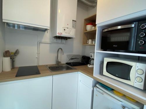 une petite cuisine avec un micro-ondes et un évier dans l'établissement Appartement Climatisé avec Balcon, Parking Privé, Wifi - Proche Thermes et Étang - FR-1-503-23, à Balaruc-les-Bains