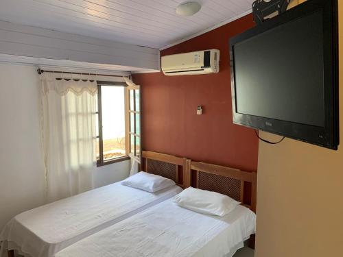 two beds in a room with a flat screen tv at Suítes Ponta Leste in Angra dos Reis