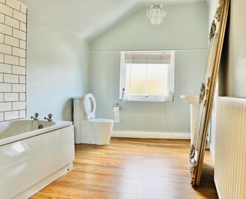 a bathroom with a tub and a toilet and a mirror at Bodhi Tree Cottage - Grove Road Cottages in Stratford-upon-Avon