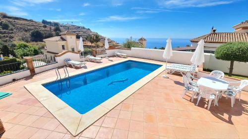 a swimming pool on a patio with a table and chairs at Nerja Villas Tamango Hill Silhouse in Nerja