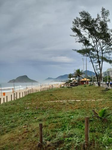 a field next to a beach with a tree at Pé na Areia in Rio de Janeiro