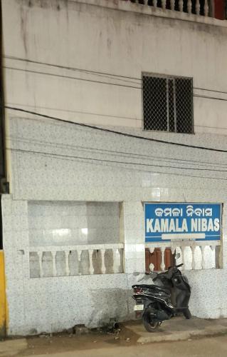 een motorfiets geparkeerd naast een gebouw met een bord bij Kamala Nivas in Puri