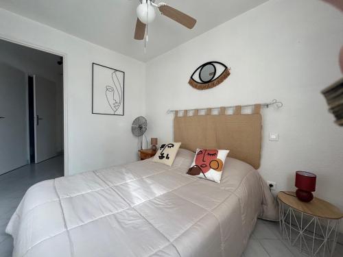 - une chambre avec un grand lit blanc et des oreillers dans l'établissement Plage et pinède à 50m de la mer, à Sète