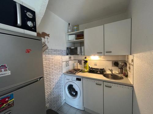 une petite cuisine avec une machine à laver et un évier dans l'établissement Plage et pinède à 50m de la mer, à Sète