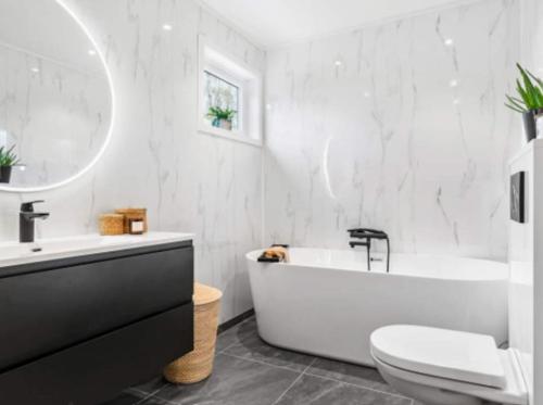 奧勒松的住宿－Stor enebolig, gratis parkering i egen garasje，白色的浴室设有浴缸、卫生间和水槽。
