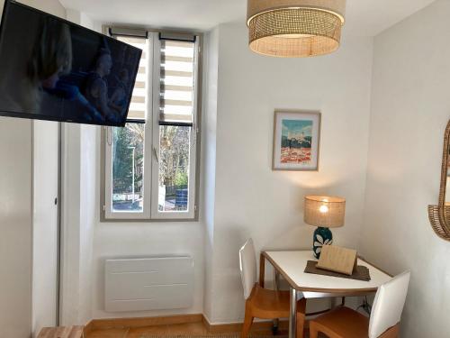 een eetkamer met een tafel en een tv aan de muur bij Studio Le Terra - Petit déjeuner inclus 1ère nuit - AUX 4 LOGIS in Foix