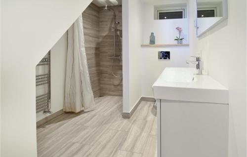 La salle de bains blanche est pourvue d'un lavabo et d'une douche. dans l'établissement Rnnebo, à Nyborg