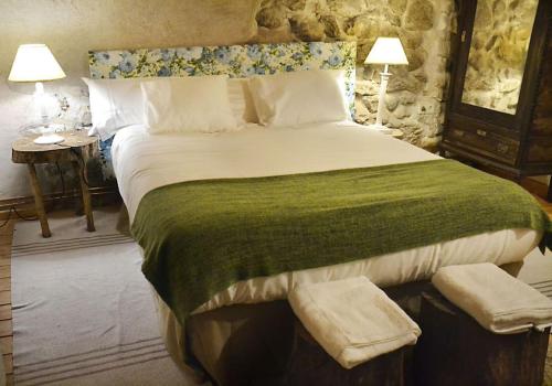 a bedroom with a large bed with a green blanket at Casa Valle del Lozoya in Rascafría