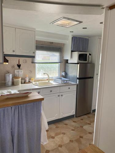 une cuisine avec des armoires blanches et un réfrigérateur en acier inoxydable dans l'établissement Mobil Home à la Pointe de Pordic, à Pordic
