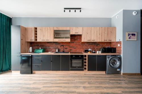 a kitchen with wooden cabinets and a brick wall at Restored Factory Residence - 55m2, Top Location - by Rentujemy in Łódź
