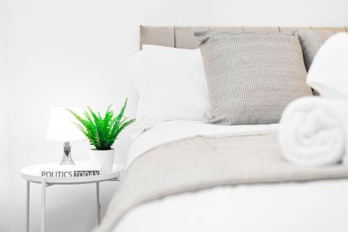 a white bed with a plant on a side table at Luxury 4 Bedroom Bungalow - Parking - Sutton Coldfield 75C in Birmingham