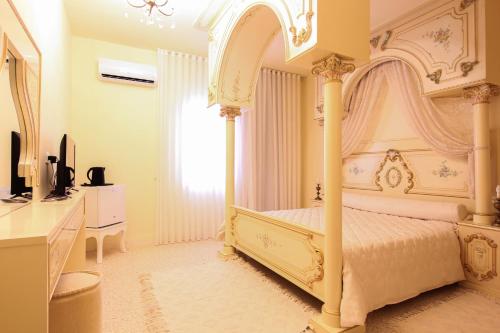 a bedroom with a white canopy bed and a television at Gîte Feki in Sfax