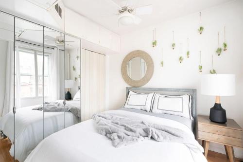 a white bedroom with two beds and a mirror at 11-4F Prime west village designer 1BR in New York