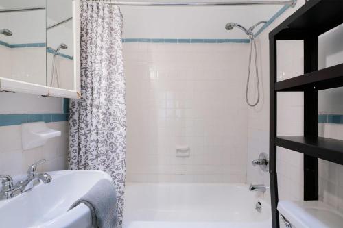 La salle de bains est pourvue d'un lavabo blanc et d'une douche. dans l'établissement 11-4F Prime west village designer 1BR, à New York