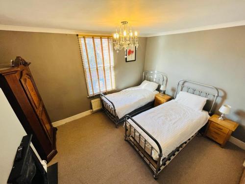 ein Schlafzimmer mit zwei Betten, einem Fernseher und einem Kronleuchter in der Unterkunft Edwards Cottage - Grove Road Cottages in Stratford-upon-Avon