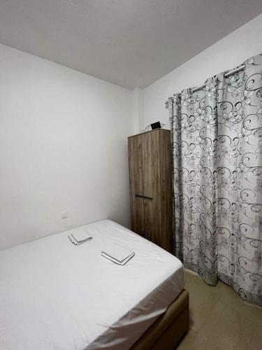 a bedroom with a bed with white sheets and a curtain at Hotel Orion Apartment in Katerini
