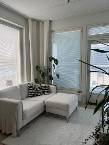 a living room with a white couch and two windows at Modern apartment in great location in Vantaa