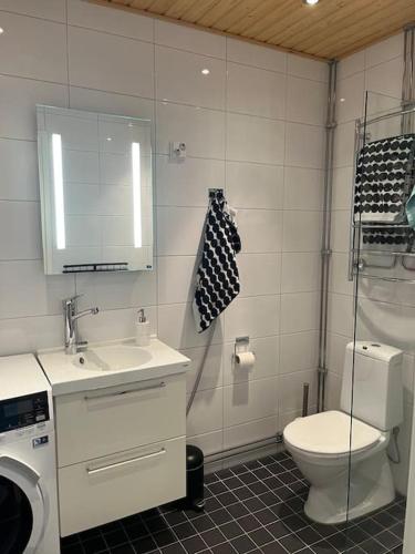 a bathroom with a toilet and a sink and a mirror at Modern apartment in great location in Vantaa