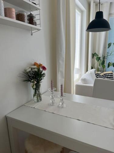 a white table with flowers in a living room at Modern apartment in great location in Vantaa