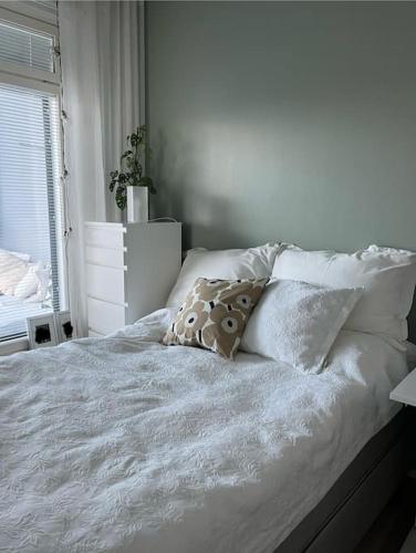 a bedroom with a white bed with pillows and a window at Modern apartment in great location in Vantaa