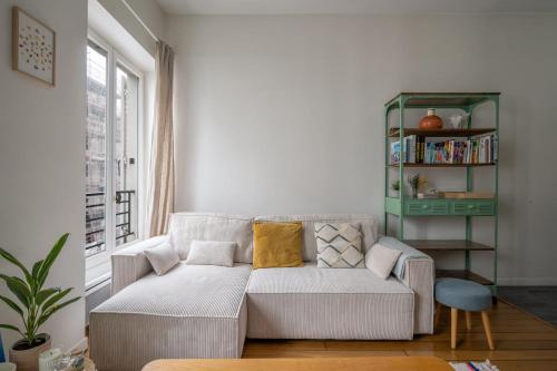 un salon avec un canapé et une étagère dans l'établissement Appartement L'Epique - Welkeys, à Paris