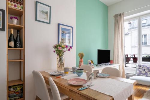 une salle à manger avec une table avec des chaises et une télévision dans l'établissement Appartement L'Epique - Welkeys, à Paris