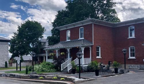 a red brick house with a porch on a street at Auberge Glengarry Inn, The Mystic 