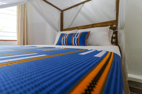 a bed with a blue and yellow striped comforter at Mayweather One Bedroom Apartment, with Beach Access, Malindi in Malindi