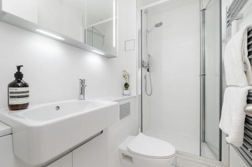 a white bathroom with a sink and a shower at Luxury Central Mayfair Townhouse with AC 3BR 3BA in London