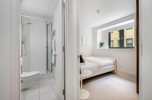 a white bathroom with a bed and a shower at Luxury Central Mayfair Townhouse with AC 3BR 3BA in London