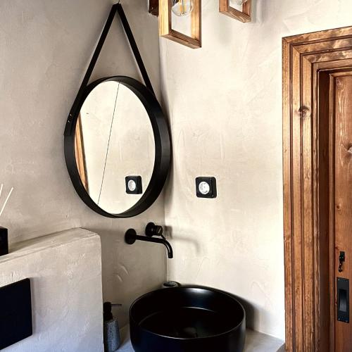 uma casa de banho com um lavatório preto e um espelho em Memories Apartments - Σοφίτα με τζάκι στο Καρπενήσι. em Karpenision