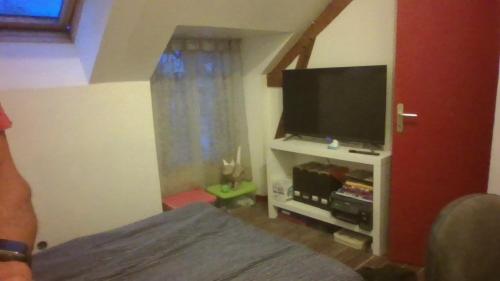 Schlafzimmer mit einem Bett und einem Flachbild-TV in der Unterkunft Chambre dans maison in Betton