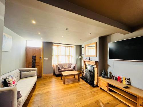 a living room with a couch and a flat screen tv at Simpsons Cottage - Grove Road Cottages in Stratford-upon-Avon