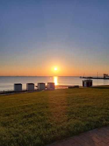 einen Sonnenuntergang über dem Wasser mit einem Pier in der Unterkunft Pension Feist Zimmer 11 in Dagebüll