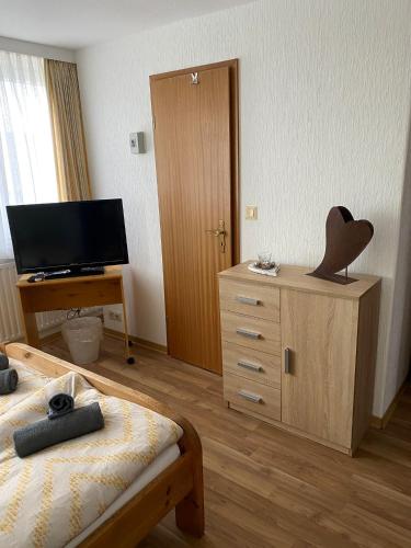 a bedroom with a bed and a dresser and a television at Pension Feist Zimmer 11 in Dagebüll