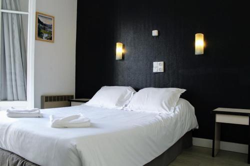 een slaapkamer met een groot wit bed en 2 handdoeken bij Hôtel Le Milan in Lourdes
