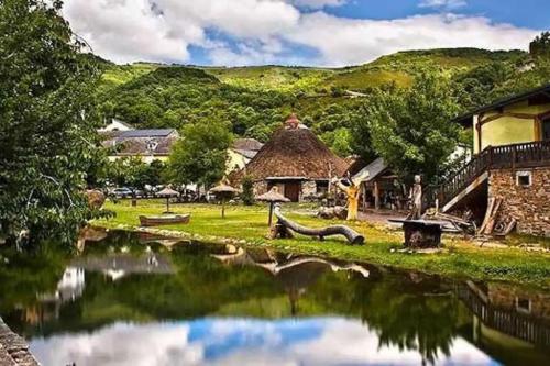 a village with a pond in front of a building at El Rincón de la Mimosa in Vega de Espinareda