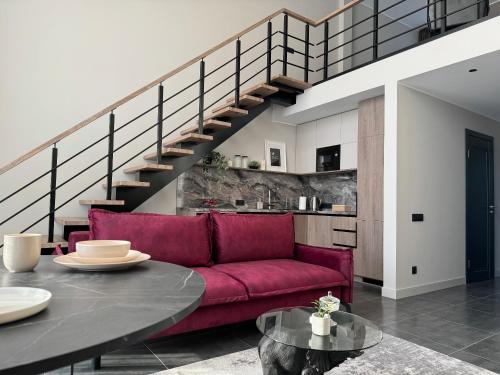 sala de estar con sofá rojo y escaleras en Cukura Loft, en Jelgava